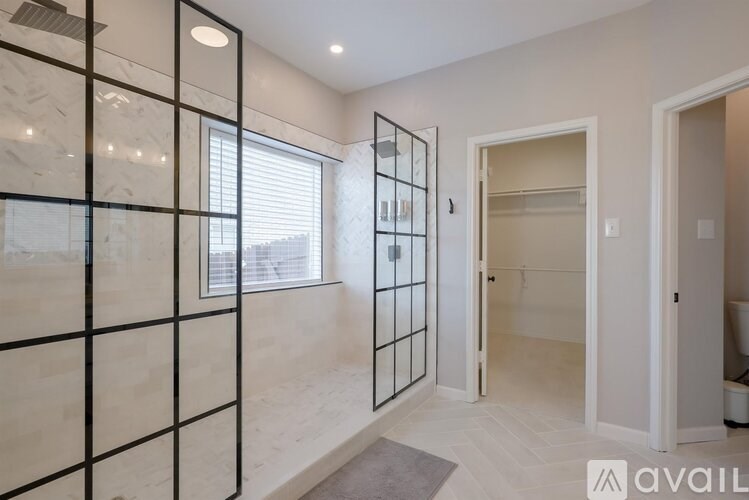 A hallway with a glass partition on the left side and a door on the right.