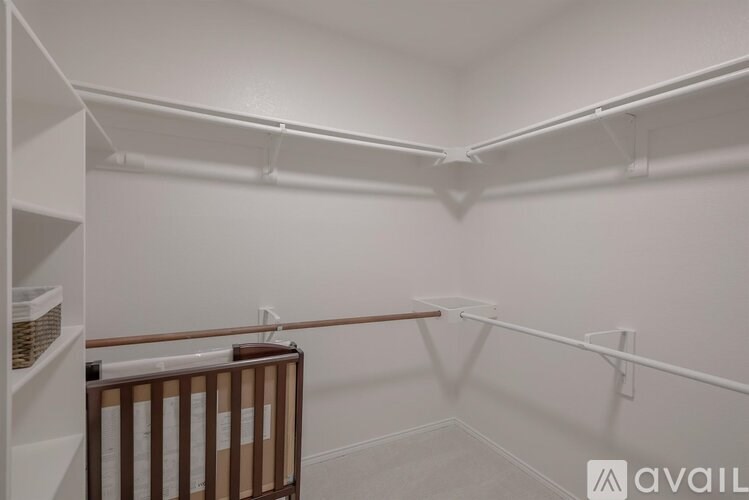 A white wall with a baby crib and a shelf.