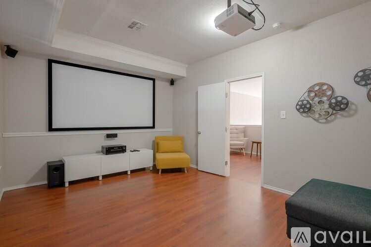 A room with a white screen, a yellow chair, and a black speaker.