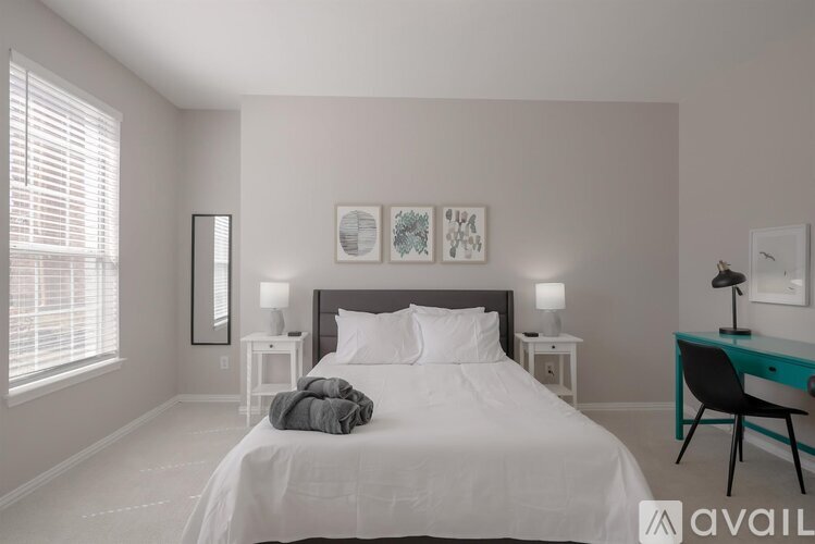 A bedroom with a large bed, a desk with a chair, and two nightstands with lamps.