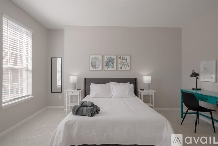 A bedroom with a large bed, a desk with a chair, and two nightstands with lamps.