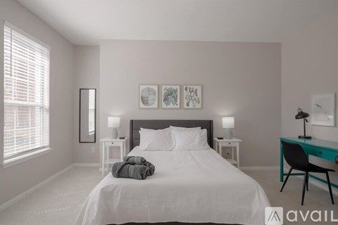 A bedroom with a large bed, a desk with a chair, and two nightstands with lamps.