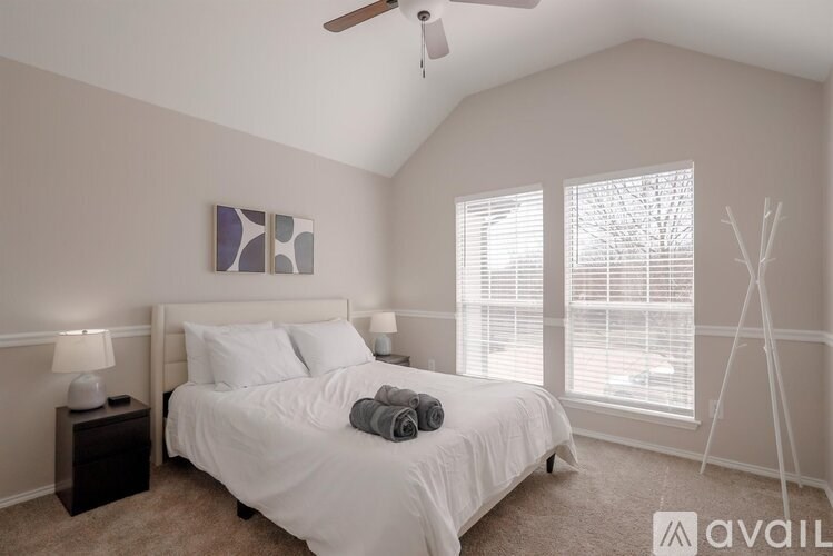 A bedroom with a bed, a ceiling fan, and a window with blinds.