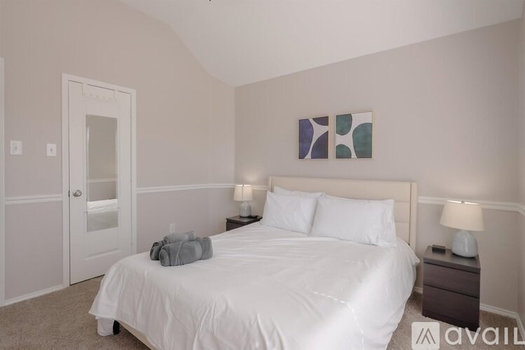 A bedroom with a large bed and a painting on the wall.