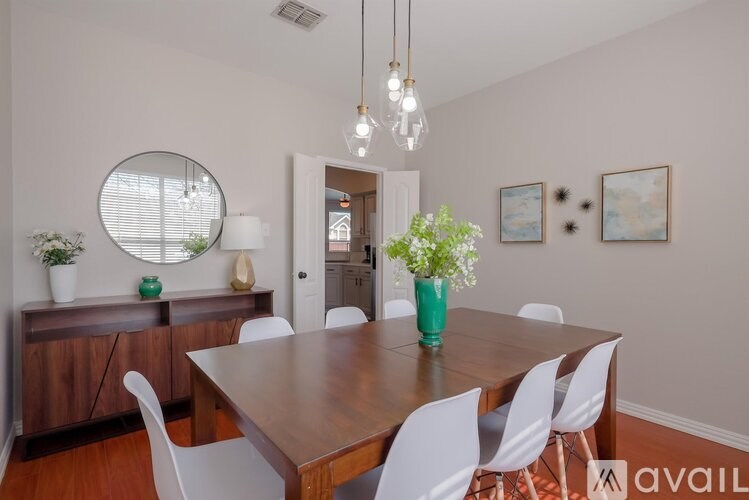 A dining room with a wooden table and white chairs.