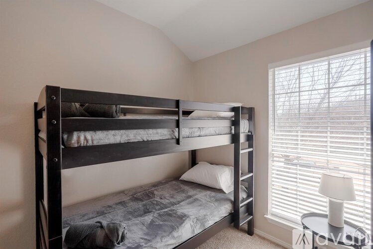 A bedroom with a bunk bed and a small table with a lamp.