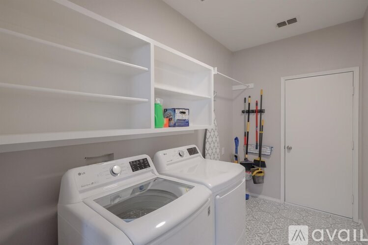 A laundry room with a washer and dryer and a white shelf above them.