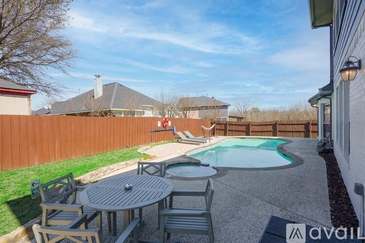 A backyard with a table and chairs and a pool.