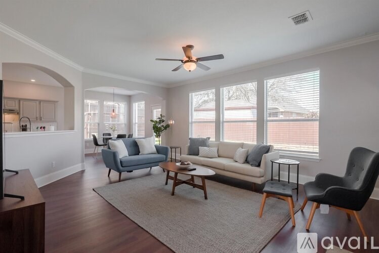 A living room with a blue couch, a coffee table, and a ceiling fan.