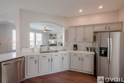 A kitchen with white cabinets and a stainless steel refrigerator.