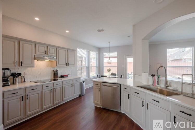 A kitchen with wooden floors and white cabinets.