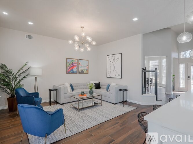 A living room with a white couch, a blue chair, and a coffee table.