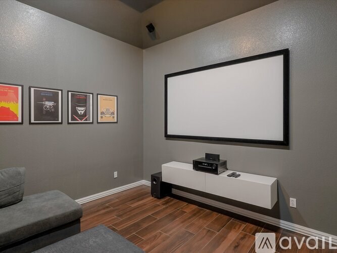 A modern living room with a grey sofa, a white bench, and a large flat screen TV.