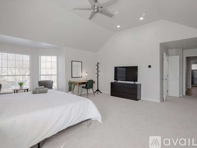 A bedroom with a large bed, a television, and a chair.