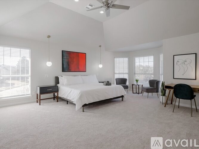 A bedroom with a large bed, a desk, and a chair.