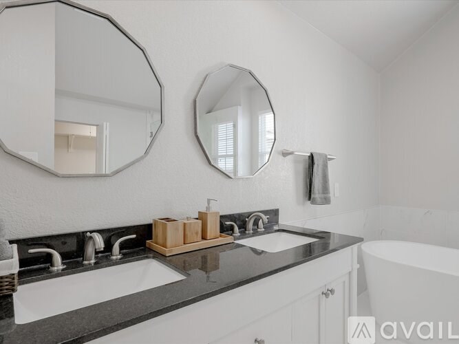 A bathroom with a white tub, two sinks, and two mirrors.