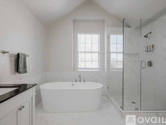 A white bathroom with a tub, sink, and shower.