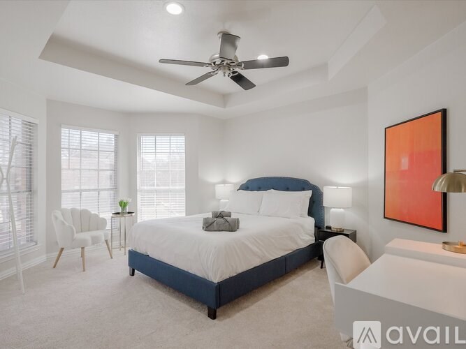 A bedroom with a bed, chair, and ceiling fan.