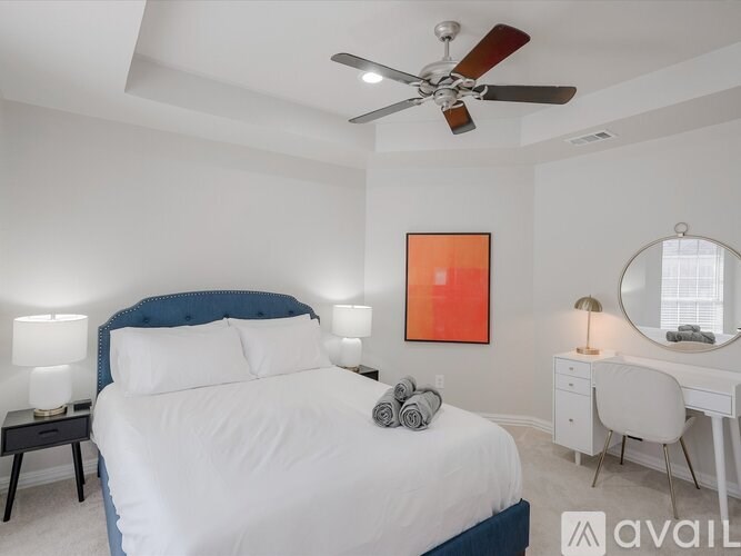 A bedroom with a bed, desk, and mirror.