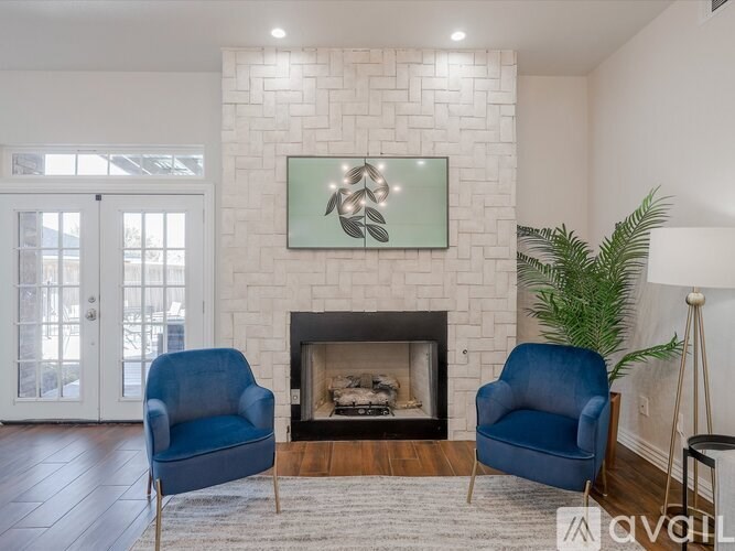 Two blue chairs are placed in front of a fireplace.