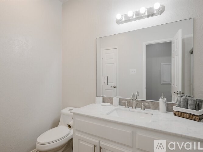 A bathroom with a white toilet, sink, and mirror.