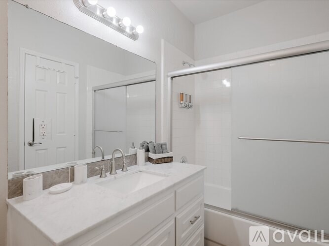 A bathroom with a white sink and a mirror with lights above it.