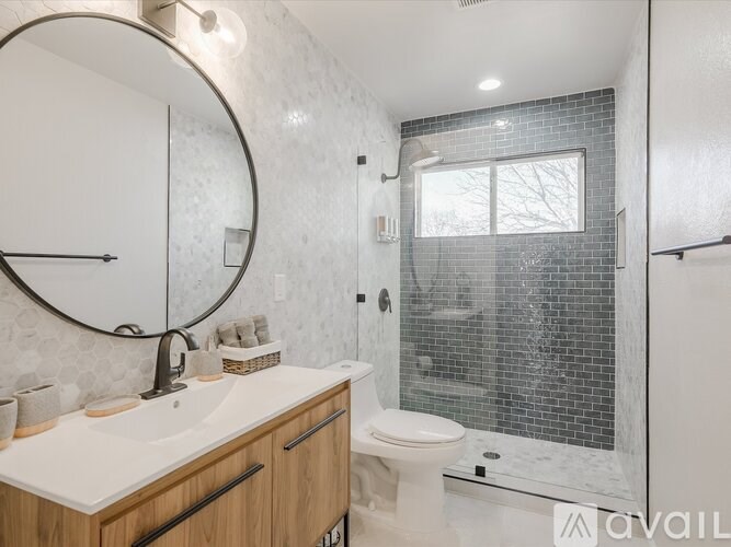 A bathroom with a white sink, toilet, and a round mirror.