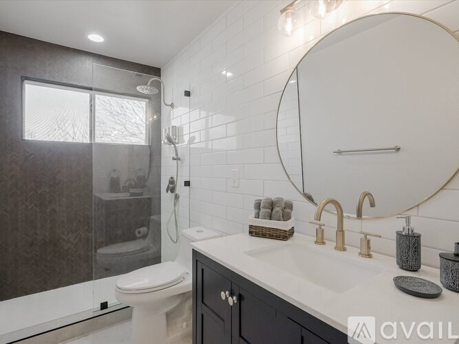 A bathroom with a toilet, sink, and mirror.