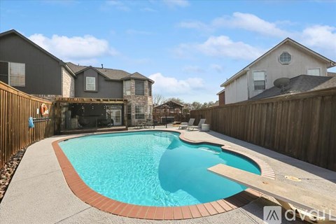 A small residential pool with a concrete border and a wooden deck.