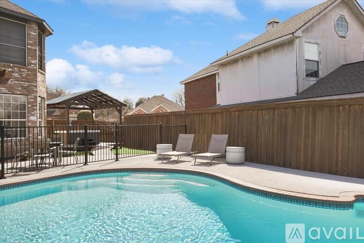 A pool with a black fence and a white chair.