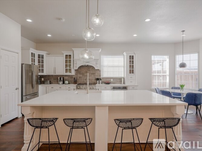 A kitchen with a white island and bar stools.