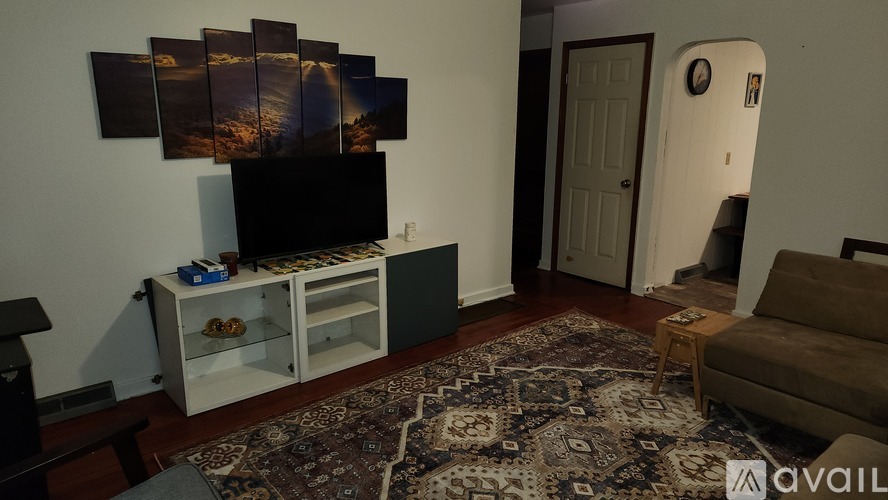A living room with a television, a rug, and pictures on the wall.