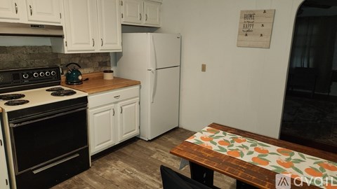 A kitchen with a white fridge and a wooden table with a floral tablecloth.