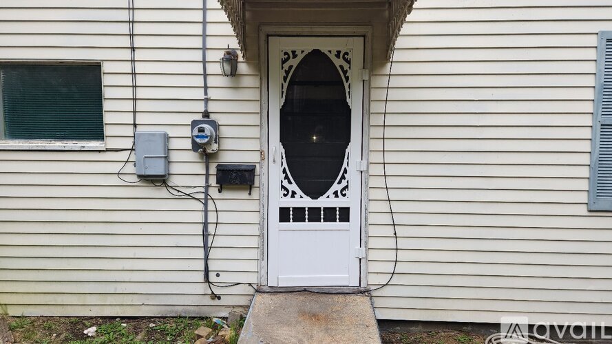 A white door with a window and a mailbox on the side of a house.