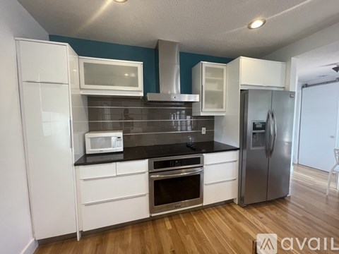 A kitchen with white cabinets and a black countertop.