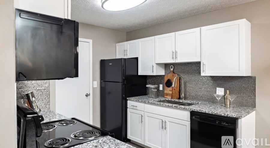 A kitchen with black appliances and white cabinets.