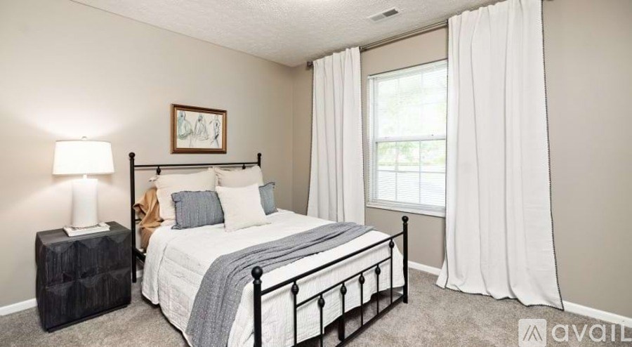 A bedroom with a bed, nightstand, and window.