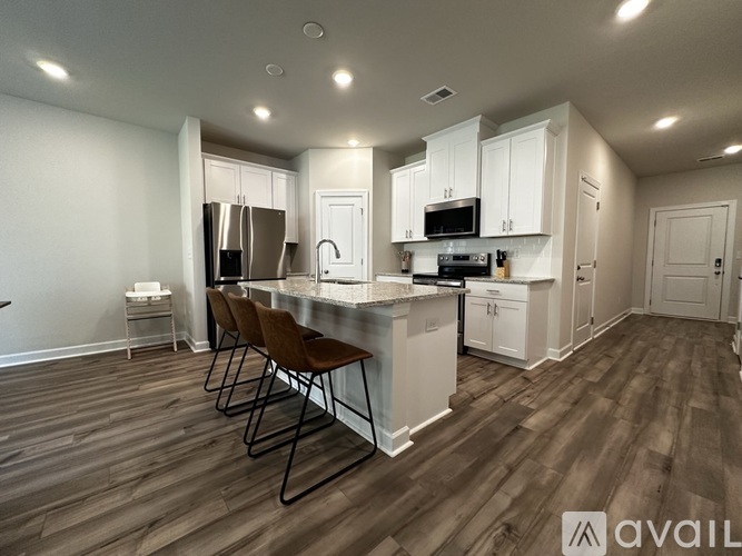 A kitchen with white cabinets and a wooden floor.