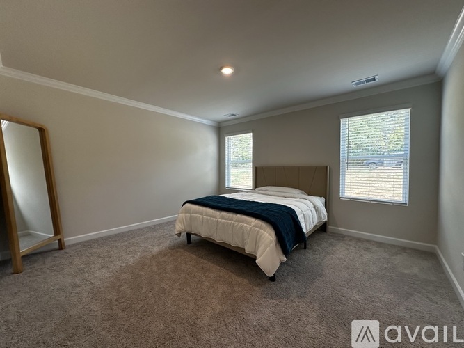 A bedroom with a bed, carpet, and a window.