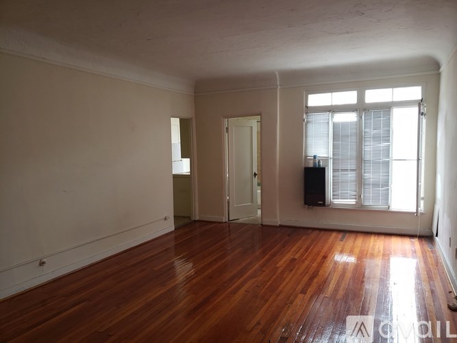 A room with wooden floors and a door leading to another room.