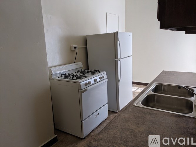 A kitchen with a stove, refrigerator, and sink.