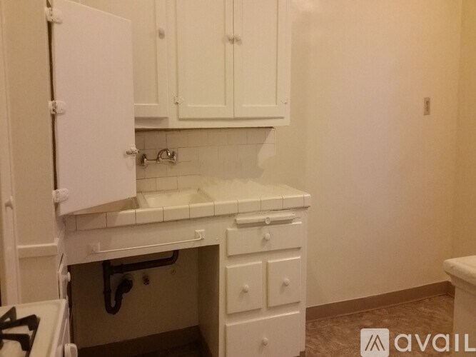 A kitchen with white cabinets and a white stove top oven.