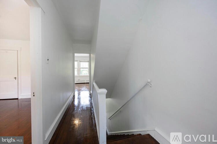 A long hallway with a staircase on the right and a door on the left.