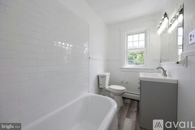 A white tiled bathroom with a tub, toilet, and sink.