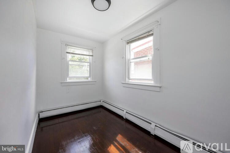 A room with two windows and wooden floors.