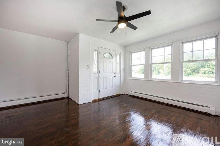 A room with a ceiling fan and wooden floors.