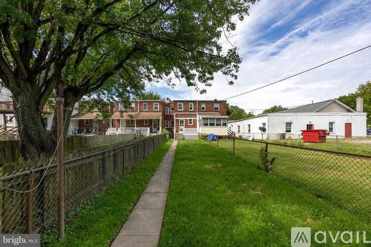 A tree-lined pathway leads to a white house with a red door.