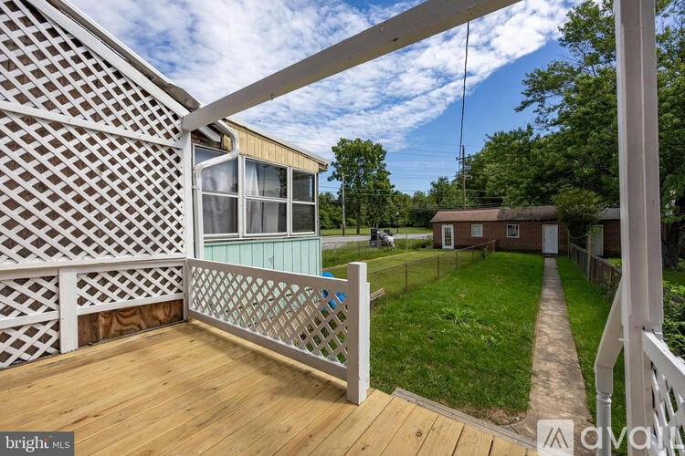 A wooden deck with a lattice fence and a view of a backyard.