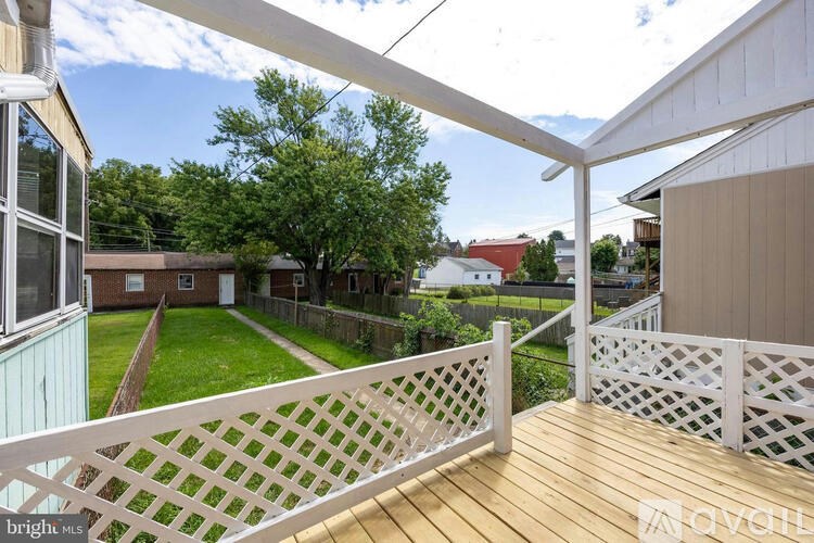 A white lattice fence on a wooden deck overlooks a green lawn and trees.