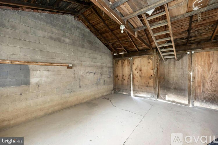 A spacious attic room with wooden beams and exposed ceiling.